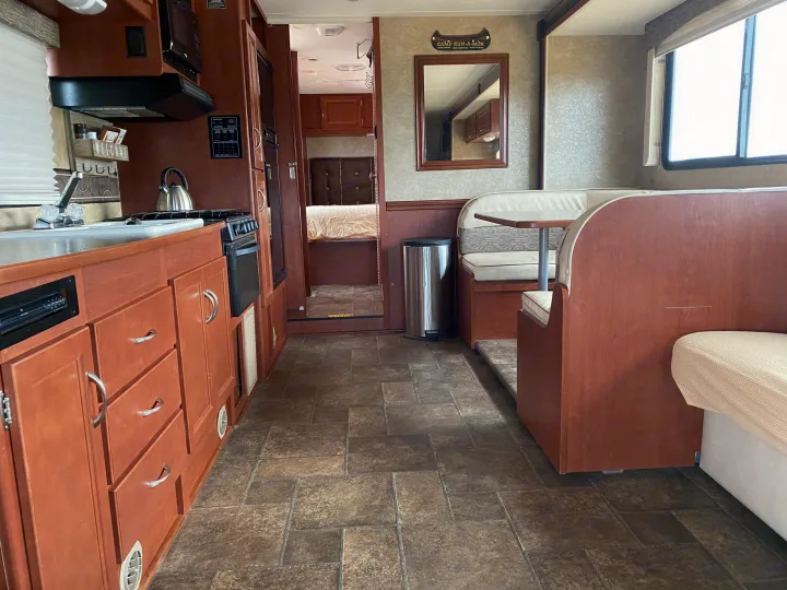 RV rental interior: compact kitchen, dinette, and bedroom entrance provide a functional living space.. Winnebago Minnie Winnie 2015