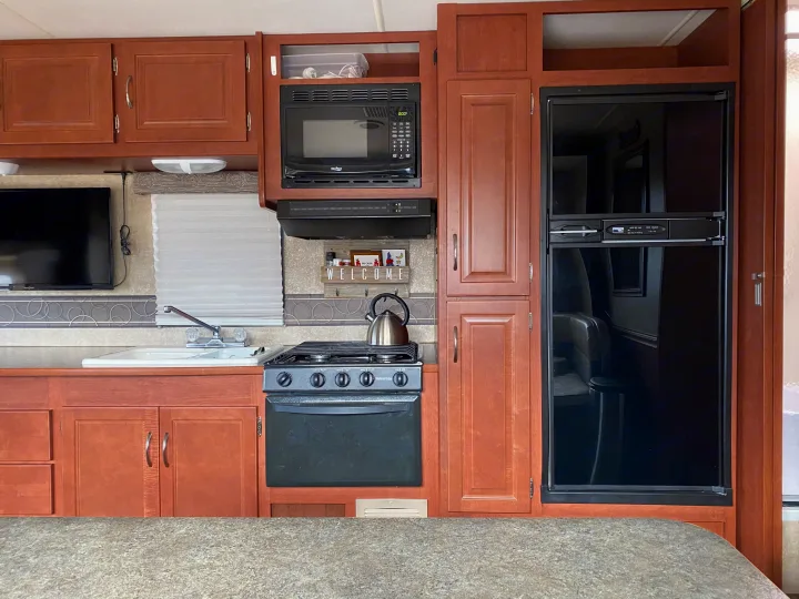 RV rental kitchen: This image shows a full kitchen setup with a sink, stove, microwave, refrigerator, and ample cabinetry.. Winnebago Minnie Winnie 2015