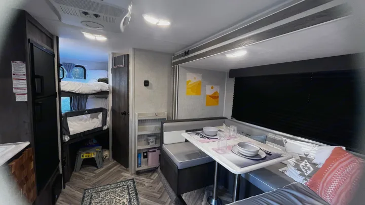 Bright RV rental interior showing a dining area, refrigerator, and cozy bunk beds. Ideal for family travel.. Forest River Wildwood FSX 2021
