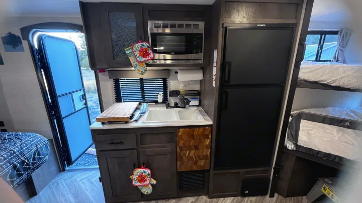 Cozy RV rental interior with a full kitchen, Dometic fridge, and bunk beds, perfect for family travel.. Forest River Wildwood FSX 2021