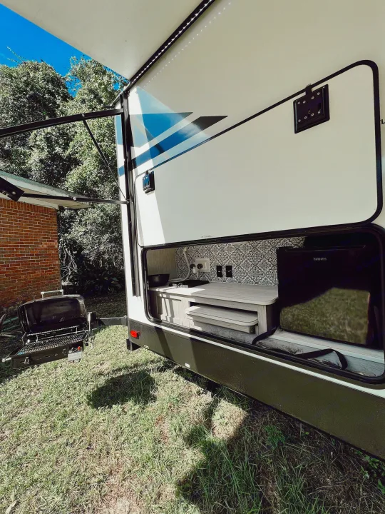 Outdoor kitchen features upgraded backsplash, mini fridge, sink, grill and slide-out countertop as a food prep station. . Heartland RVs Mallard 2021