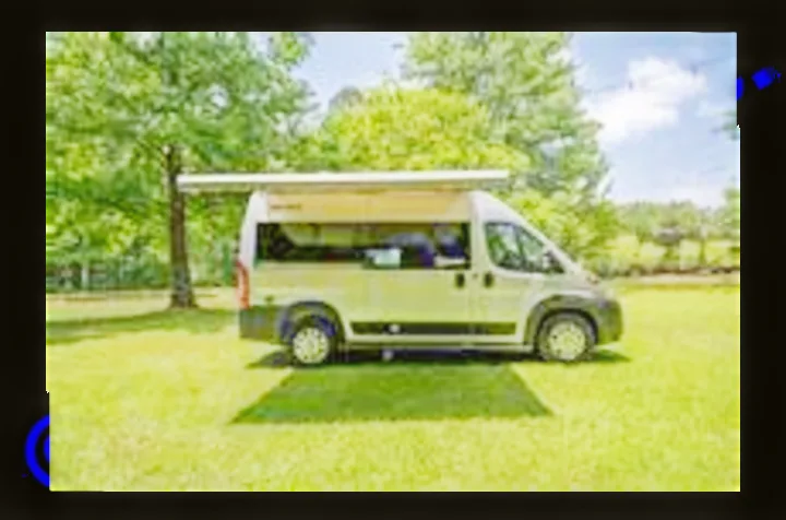Parked on lush green grass, this gray RV rental offers an extended awning for comfortable outdoor adventures.. Thor Scope 2022