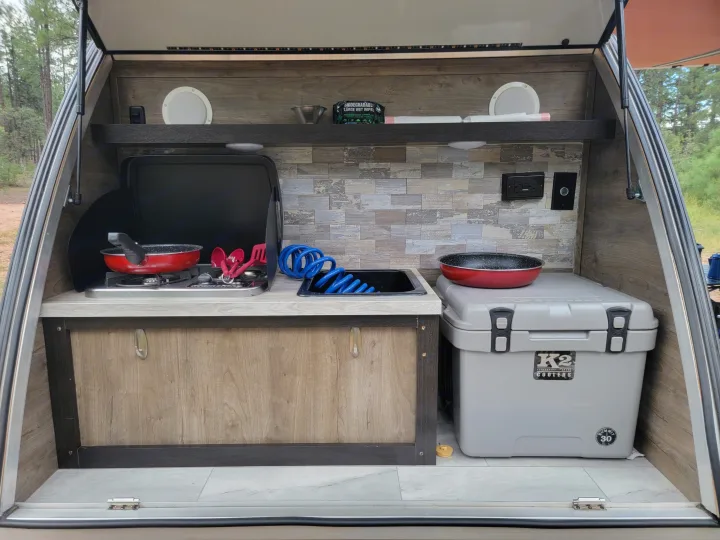 This RV rental's outdoor kitchen features a stove, sink, and cooler for camping adventures.. Braxton Creek Free Solo 2022