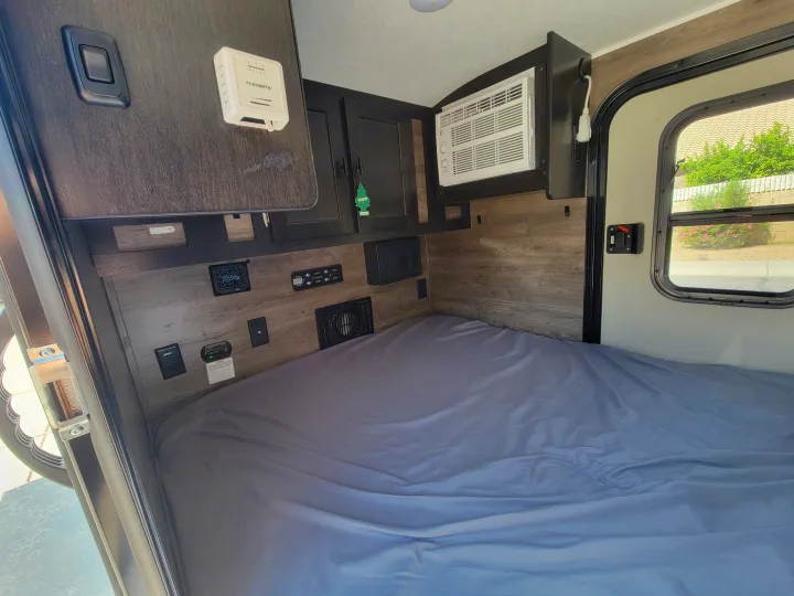 Step into this RV rental's cozy interior, featuring a comfortable bed, AC, thermostat, and essential controls.. Braxton Creek Free Solo 2022
