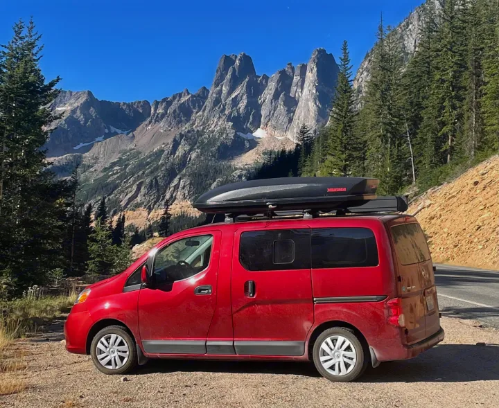 Exploring scenic mountains in a red camper van RV rental, fully equipped with a roof cargo box.. Nissan Elgrand 2021