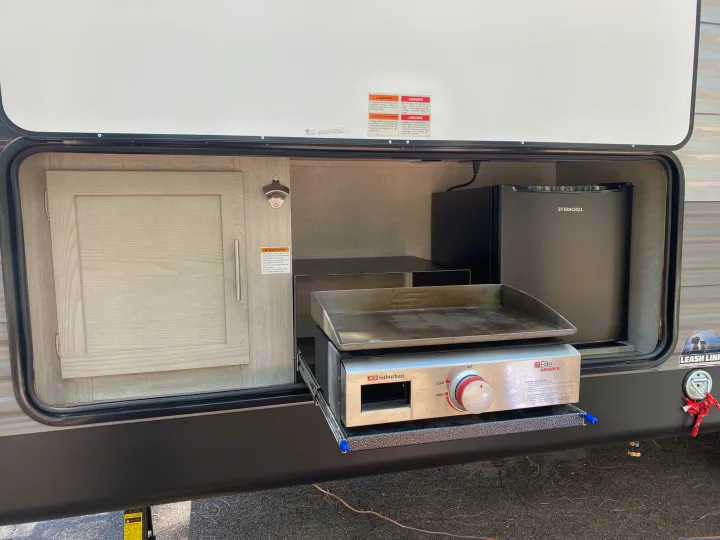 RV rental outdoor kitchen: pull-out griddle, mini-fridge, and bottle opener, perfect for camping.. Forest River Coachmen Catalina Legacy 2022