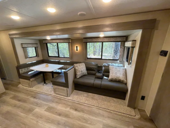 Explore this RV rental's inviting interior: a comfortable U-shaped dinette and theater-style sofa in a spacious living area.. Forest River Coachmen Catalina Legacy 2022