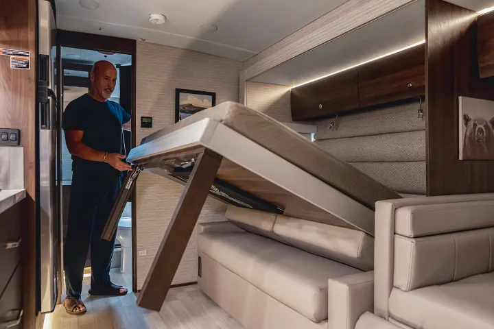 Man operating a space-saving pull-down bed inside an RV rental. Optimize your RV interior for comfort!. Winnebago View 2025