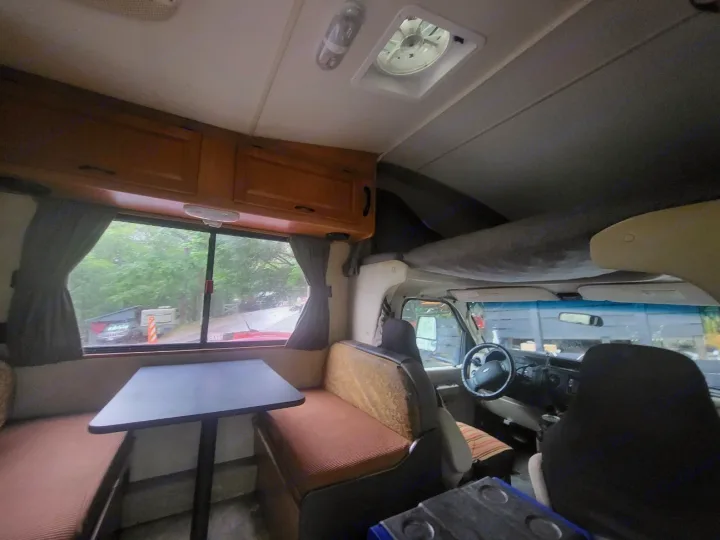 Interior view of an rv rental showing a dinette, overhead bunk, and the front driving area, ideal for travel.. Thor 2012 Thor 19G 2012