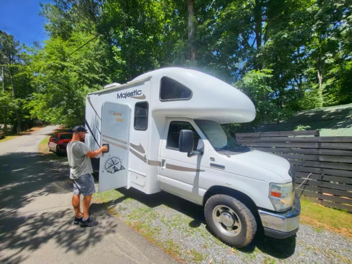 A man opens the door of a white Majestic RV rental, ready for an outdoor adventure or road trip.. Thor 2012 Thor 19G 2012