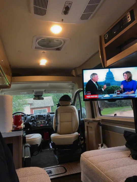 An RV rental's inviting interior. Watch news on TV from comfy seating, with the driver's area visible beyond.. Winnebago Travato 2019