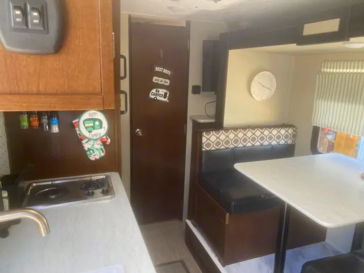 RV rental interior: A compact kitchen with stovetop/sink and a comfy dining booth/table, ideal for road trips.. PTX Forest River PDX170 2019