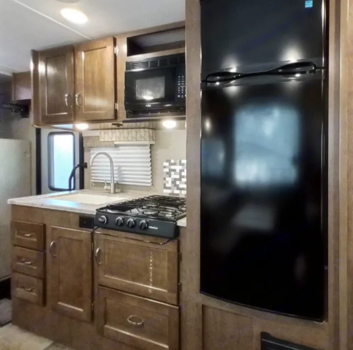Modern RV rental kitchen with all appliances: fridge, microwave, stove, and sink.. Winnebago Outlook 2019