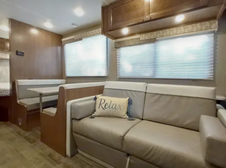 Cozy RV rental interior featuring a comfortable sofa, dinette, and bright windows.. Winnebago Outlook 2019