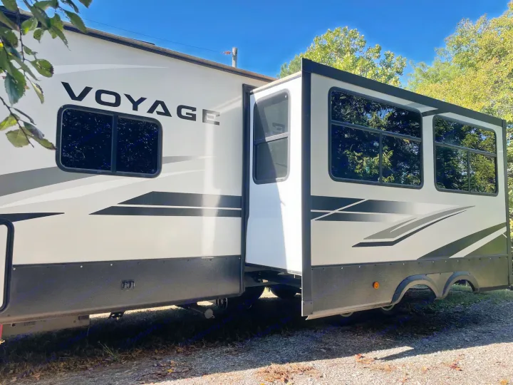 White Voyage RV rental with extended slide-out at a sunny campsite. Ready for adventure!. Winnebago Voyage 2021
