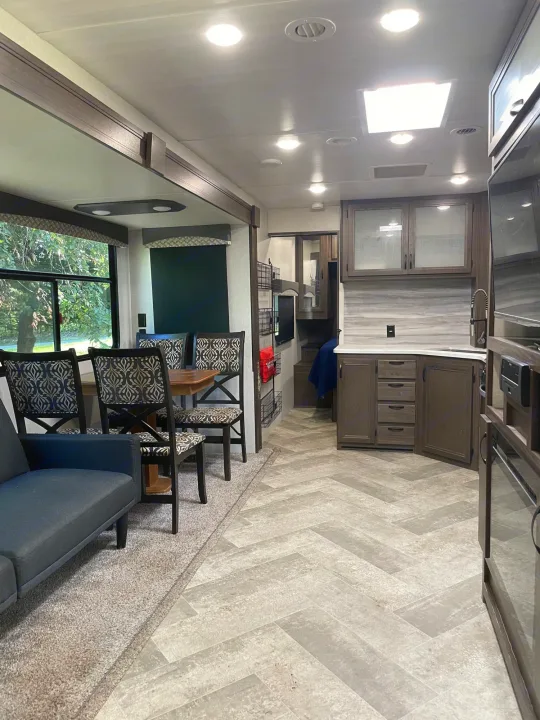 Modern RV rental interior: cozy living, dining with patterned chairs, & sleek kitchen. Bright for travel.. Winnebago Voyage 2021