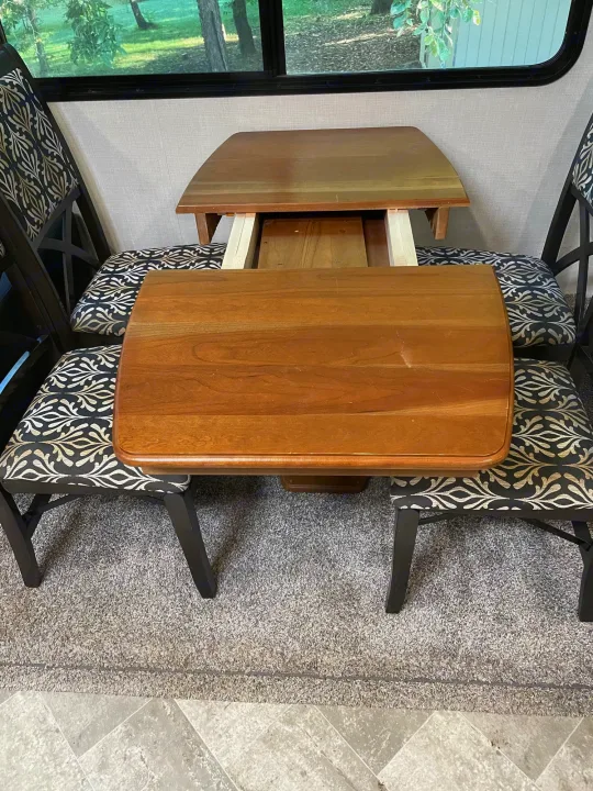 Cozy RV rental dinette with an extendable wooden table and patterned chairs, ideal for travel meals.. Winnebago Voyage 2021