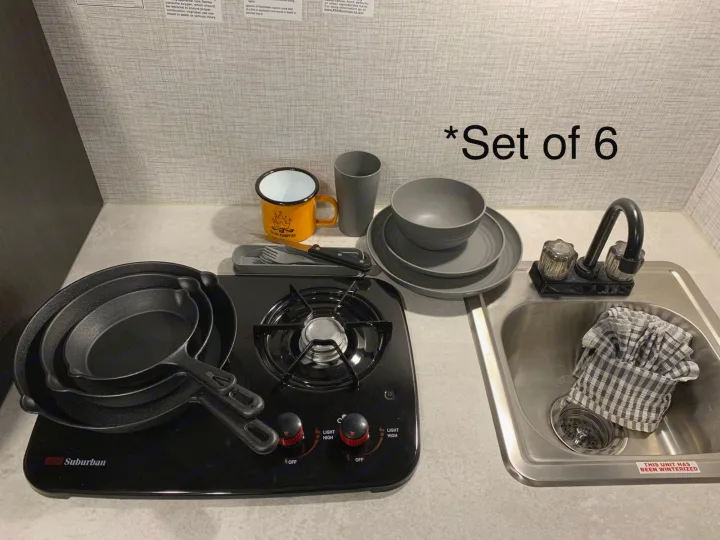 RV rental kitchen essentials: Compact stove, cast iron pans, dinnerware for 6, and sink. Perfect for camp cooking!. Coleman’s Bushwhacker Plus 2024