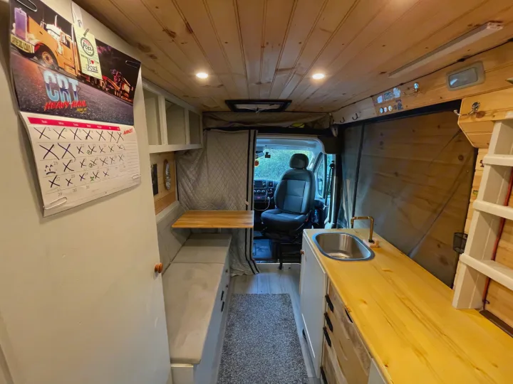 Check out this RV rental's camper van interior, featuring a kitchen, fold-out table, and cozy sleeping area.. Dodge Other 2018