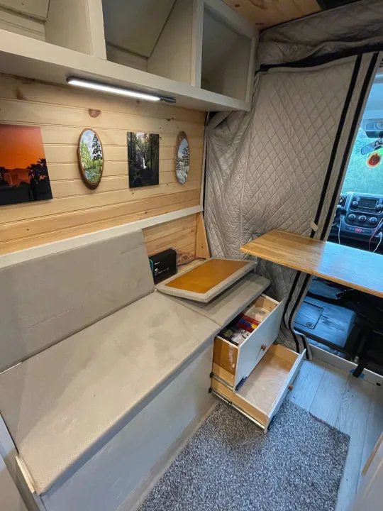 RV rental interior: A cozy space with light wood walls, a cushioned bench, art, pull-out storage, and a side table.. Dodge Other 2018