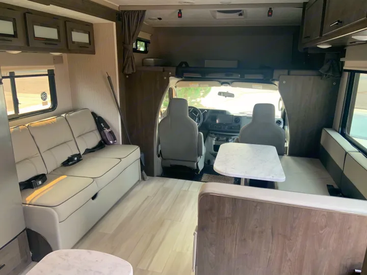 Explore this bright rv rental interior, featuring a living area, dinette, and front cockpit. Modern design for travel.. Coachmen Leprechaun 2022