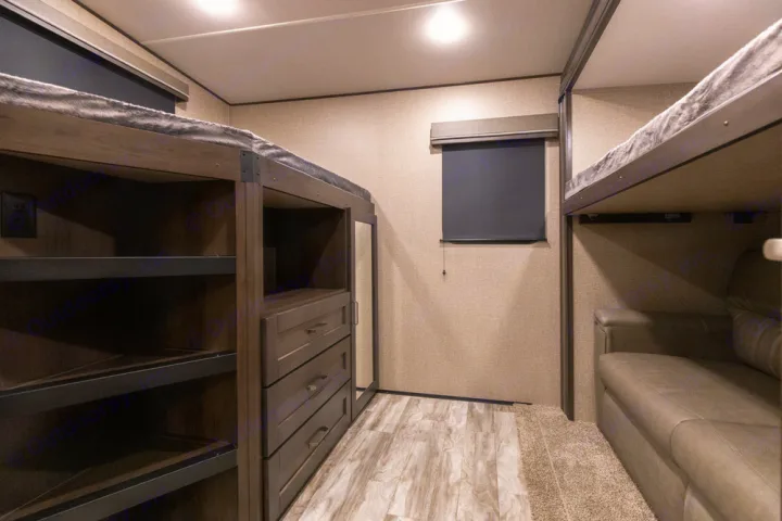 RV rental bunkhouse features: built-in storage, dresser, window, and a sofa under upper bunks. Ideal for family travel.. Grand Design Reflection 2021