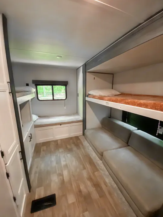 RV rental interior: Cozy bunk beds and spacious seating area for your travels, featuring light wood flooring.. Keystone RV Hideout 2022