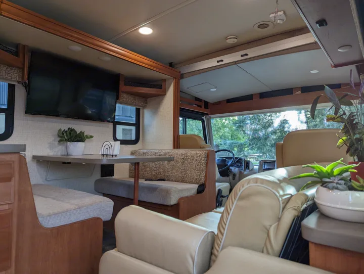 Comfortable RV rental interior featuring a spacious dining area, TV, and driver's cabin. Ideal for travel.. Winnebago Vista 2018