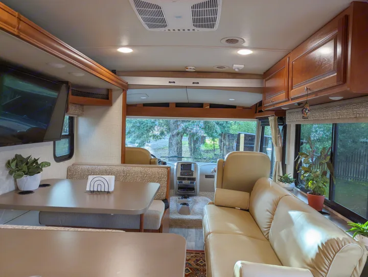 This RV rental's inviting interior showcases a dining booth, sofa, and driver's area, perfect for travel comfort.. Winnebago Vista 2018