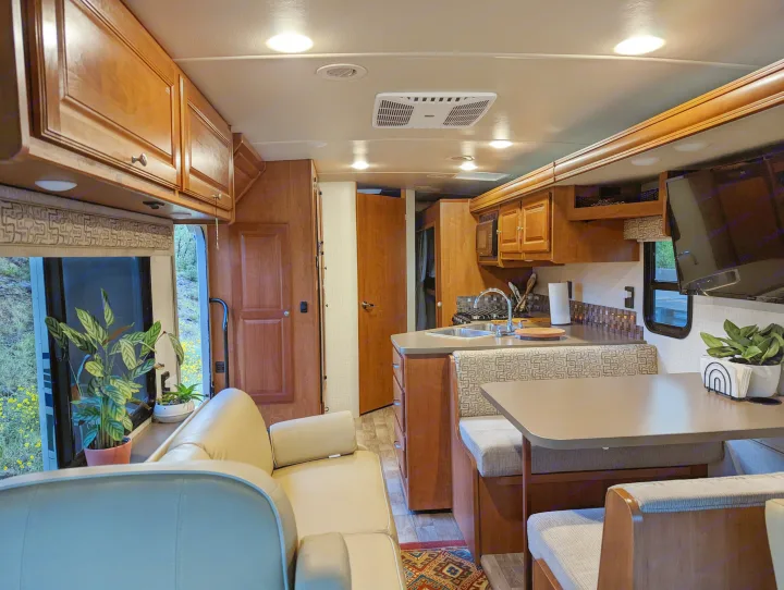 Spacious RV rental interior with a cozy sofa, well-equipped kitchen, and dining area, perfect for travel adventures.. Winnebago Vista 2018