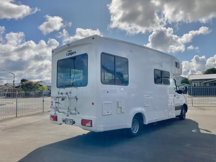 White Palmy Campers rv rental, equipped with a bike rack, parked outdoors under a cloudy sky.. Mercedes-Benz Sprinter 2022