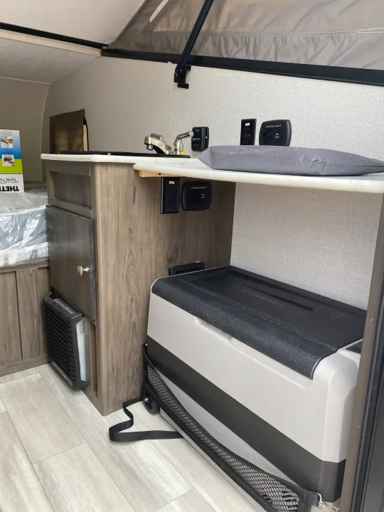 RV rental interior with kitchenette, sink, charging station, portable fridge, and heater unit near the sleeping area.. Coachmen Clipper Express 9.0 TD 2022