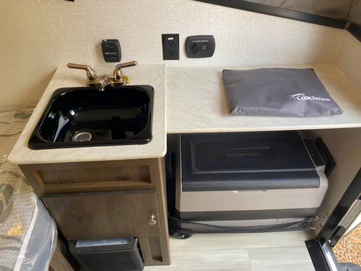 This RV rental kitchenette features a sink, thermostat, charging station, and an EverChill portable cooler/fridge.. Coachmen Clipper Express 9.0 TD 2022