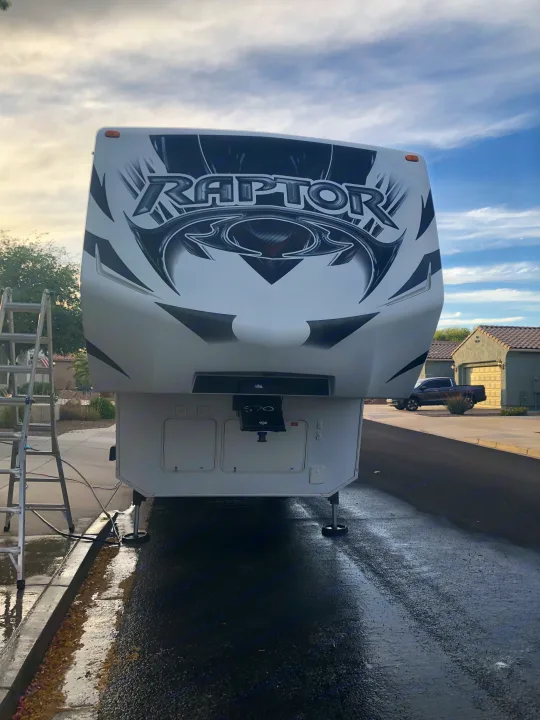 Front view of a large white Raptor fifth-wheel RV being cleaned, a great option for an RV rental adventure.. Keystone Raptor 2014