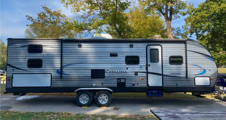 Side view of a parked Coachmen Catalina travel trailer with striped grey siding. Ideal for an rv rental vacation.. Coachmen 5ZT2CAUB5JU029455 2018