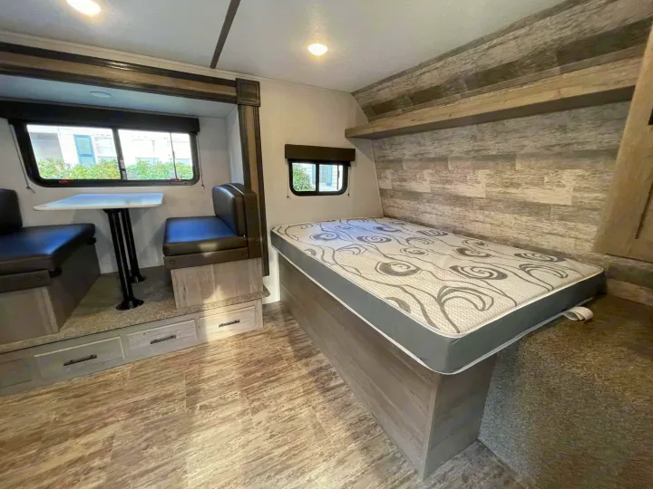 Spacious RV rental interior featuring a dinette, comfortable bed, and light wood-look finishes for a cozy stay.. Keystone RV Springdale 2021