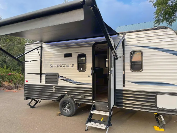 Springdale Mini travel trailer, an ideal RV rental, set up with awning extended, steps down, and jacks deployed.. Keystone RV Springdale 2021