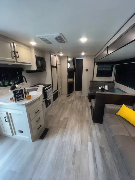 Modern RV rental interior with kitchen, dining booth, and living area. Light finishes throughout for a spacious feel.. Jayco Jay Flight 267BH 2023