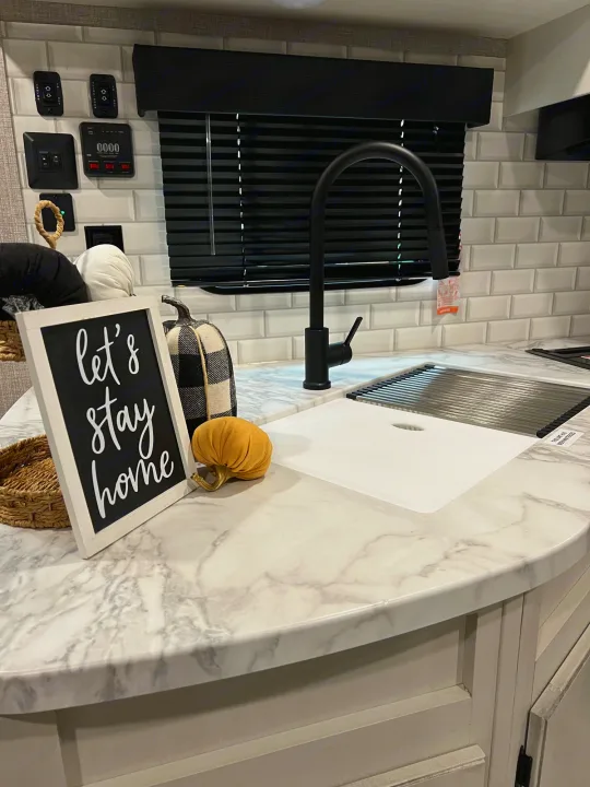 Cozy RV rental kitchen showcasing a sink, stylish faucet, marbled counter, and RV system controls on a tiled wall.. Jayco Jay Flight 267BH 2023