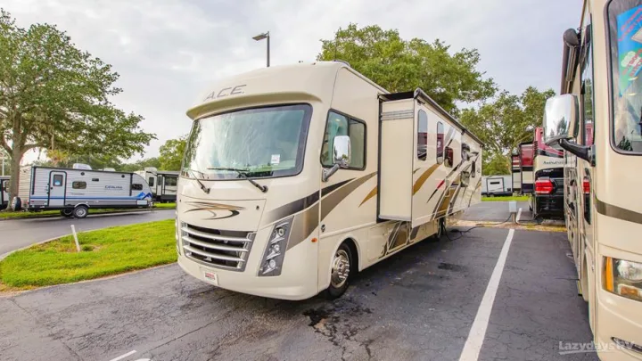 Spacious tan Class A motorhome with slide-out extended, parked in an RV lot among other campers, great for rv rental options.. Thor A.C.E. 2020