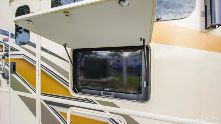 Side of an RV rental with a beige hatch open, revealing an outdoor flat-screen TV and soundbar.. Thor A.C.E. 2020