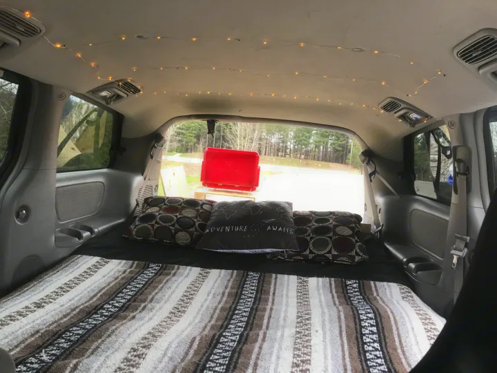 Cozy RV rental interior: a converted vehicle with bed, blanket, string lights, ready for adventure.. Toyota Sienna 2010