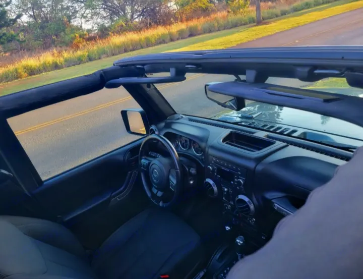 Interior of an open-top vehicle with a sunny road view. Imagine the freedom—like exploring with an RV rental!. Jeep Wrangler 2017