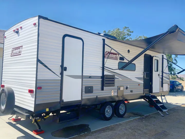Ready for adventure! This Coleman RV rental travel trailer is parked with its awning out & stabilization jacks down.. Dutchmen Coleman Lantern 2021