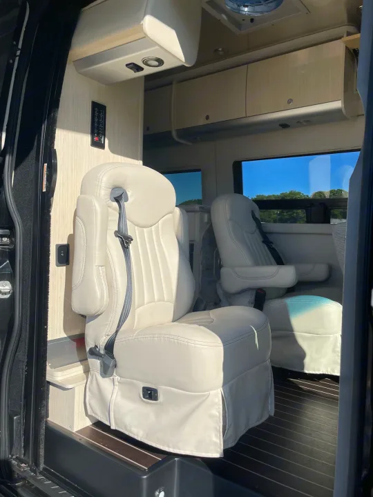 Inside this spacious RV rental: plush cream seats, wood floor, and controls. Enjoy comfortable road trips.. Airstream Interstate 2018