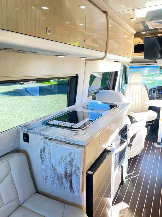 Bright RV rental interior with compact kitchen, light wood cabinets, and comfortable seating.. Airstream Interstate 2018