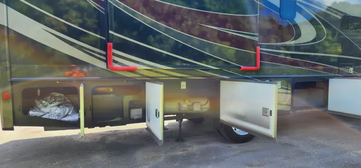 RV rental showing open side storage bays for gear, including a propane tank. Red safety padding protects the awning arms.. Bounder Bounder Motorhome 2021