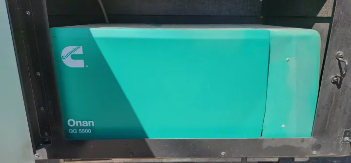 A teal Cummins Onan QG 5500 generator, typically used in an RV rental, sits within a dark compartment.. Bounder Bounder Motorhome 2021