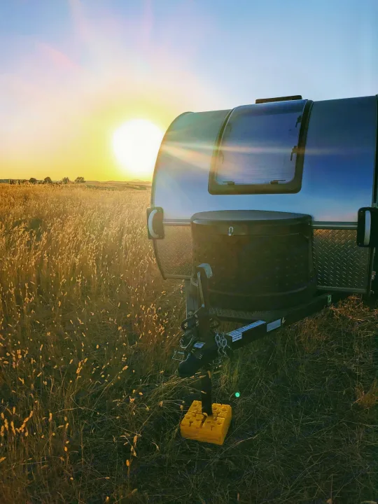 Stunning RV rental sunset! Small silver camper parked in a sun-drenched golden field of tall grass.. T@G XL 2016
