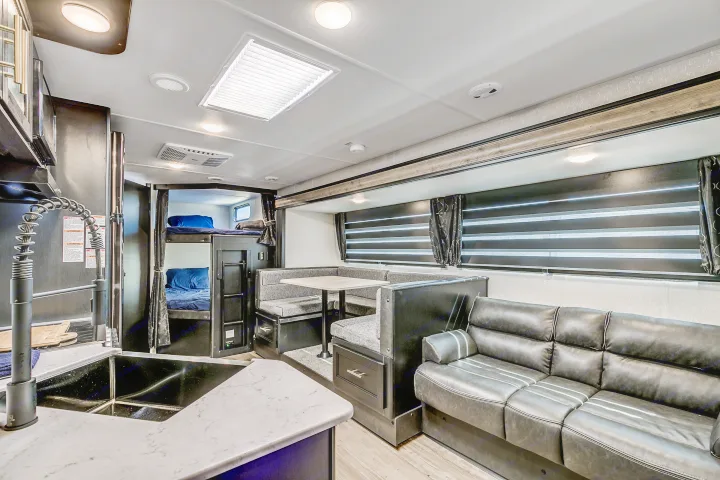Explore this modern RV rental interior: spacious kitchen, cozy bunk beds, a dining booth, and comfortable sofa.. Cherokee Grey Wolf 2022